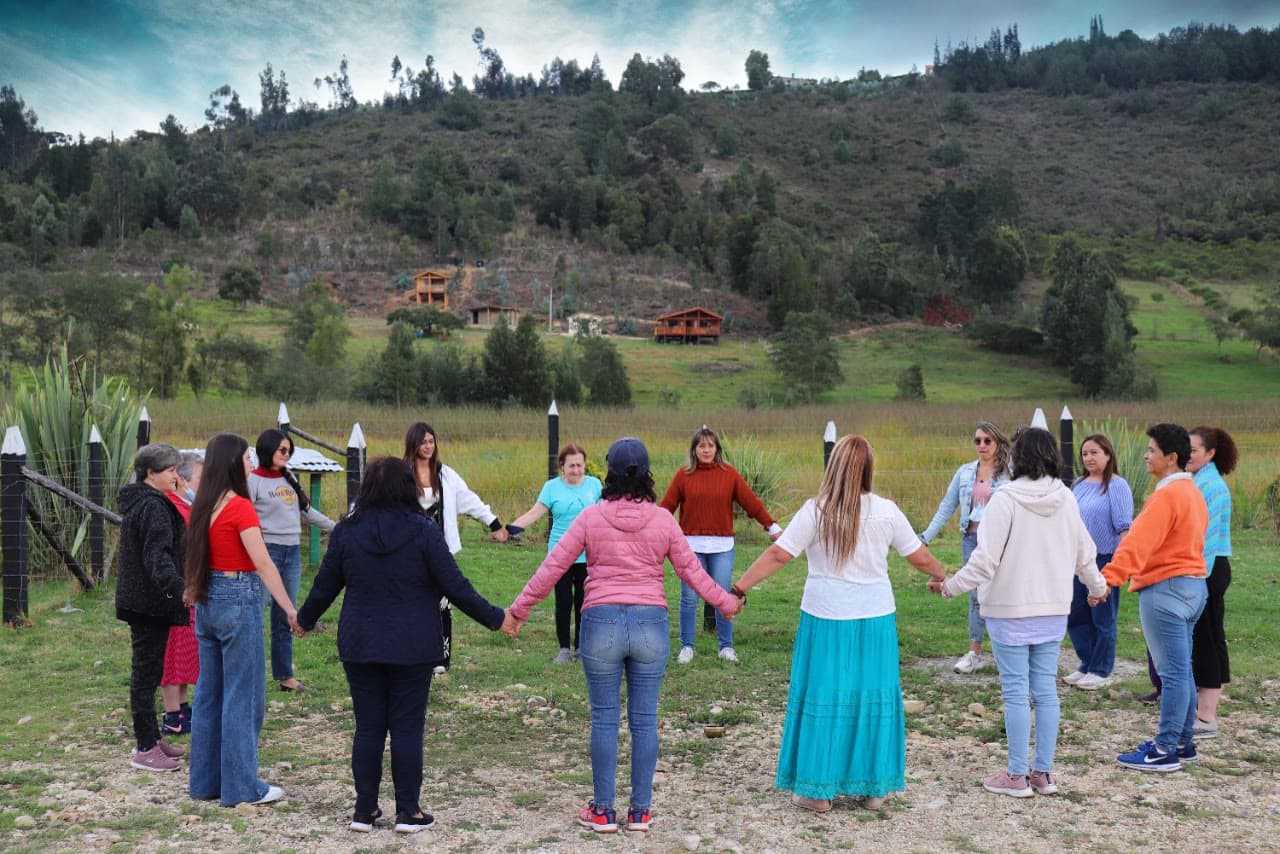 Grupo tomado de las manos en círculo en una pradera de Paipa