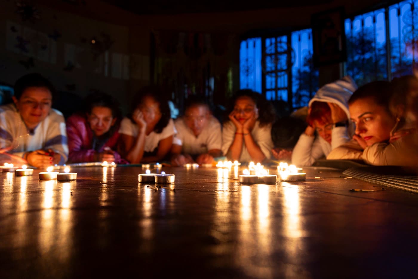 Grupo meditando frente a velas en el piso